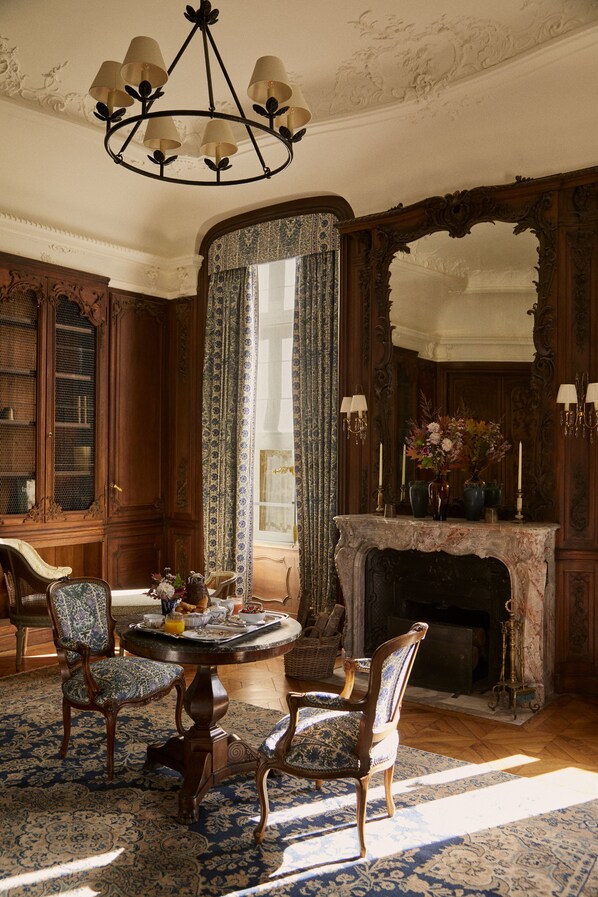 A traditional room with a fireplace, ornate wooden furniture, and a chandelier.