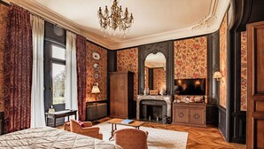 Une chambre spacieuse avec un grand lit, une cheminée, une télévision et une vue sur l’extérieur.