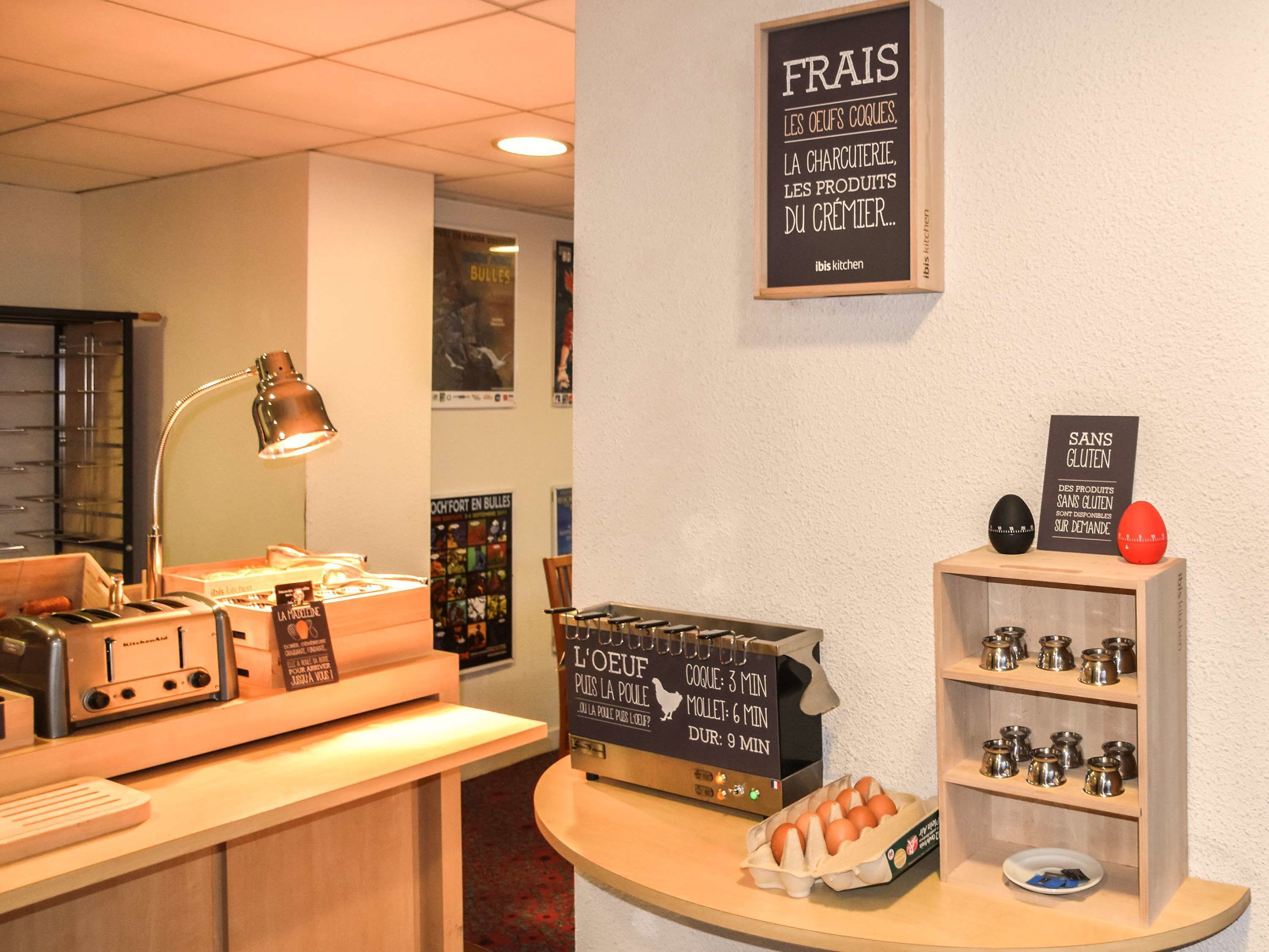 Een keukenhoek met een koffieapparaat, een bordje dat glutenvrije producten aangeeft, en een presentatie van kleine metalen bakjes.