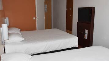 A hotel room with two beds, a wooden wardrobe, a television, and a door leading to another room.