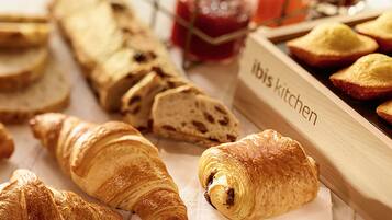Variedad de productos horneados, como cruasanes y pan, con una etiqueta que dice 'Ibis Kitchen'.