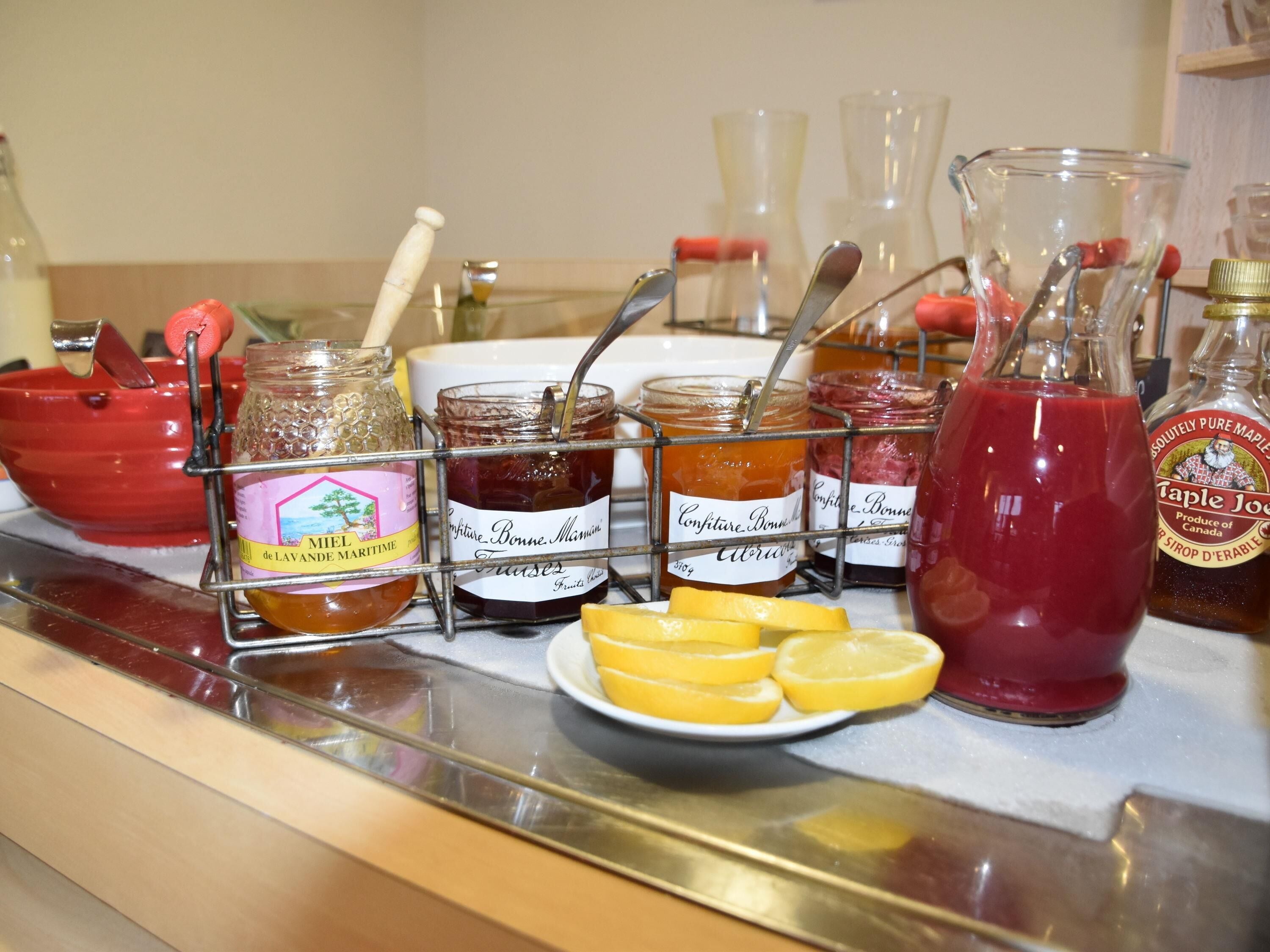 Diversos productos alimenticios, incluyendo frascos de miel, conservas y una botella de sirope de arce, sobre una encimera.