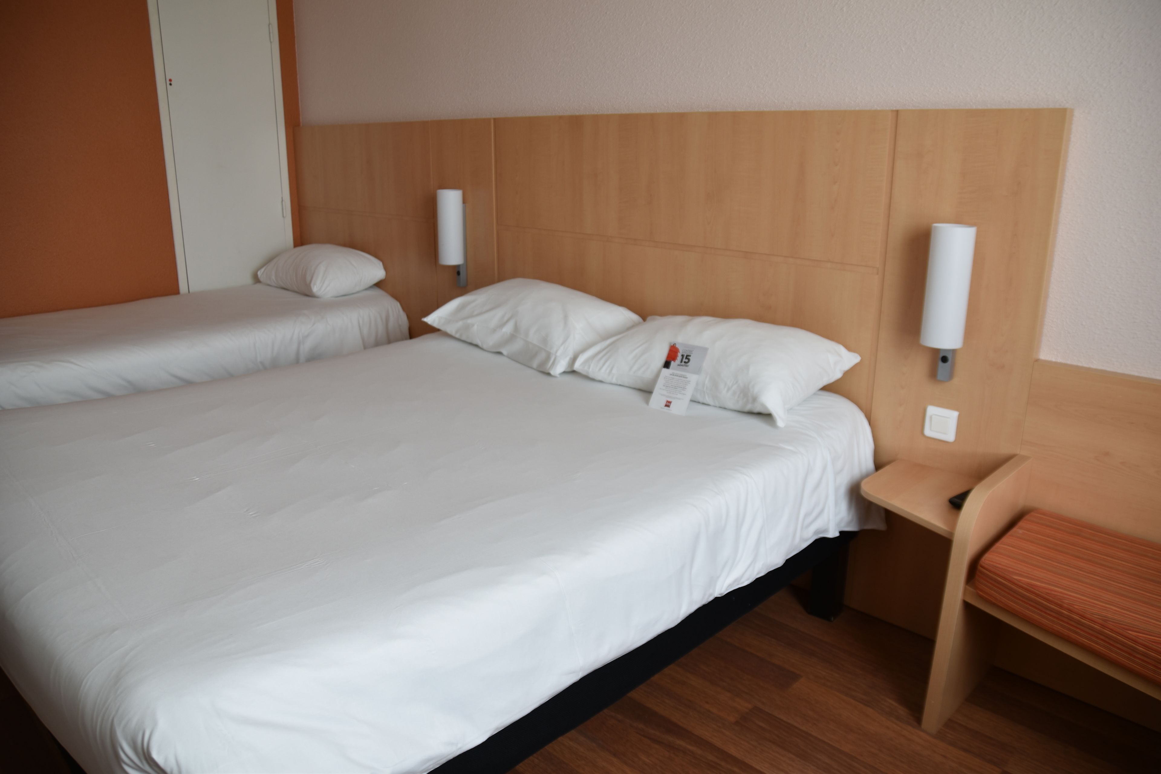 A double bed with white linens, two bedside tables, and a wooden headboard.