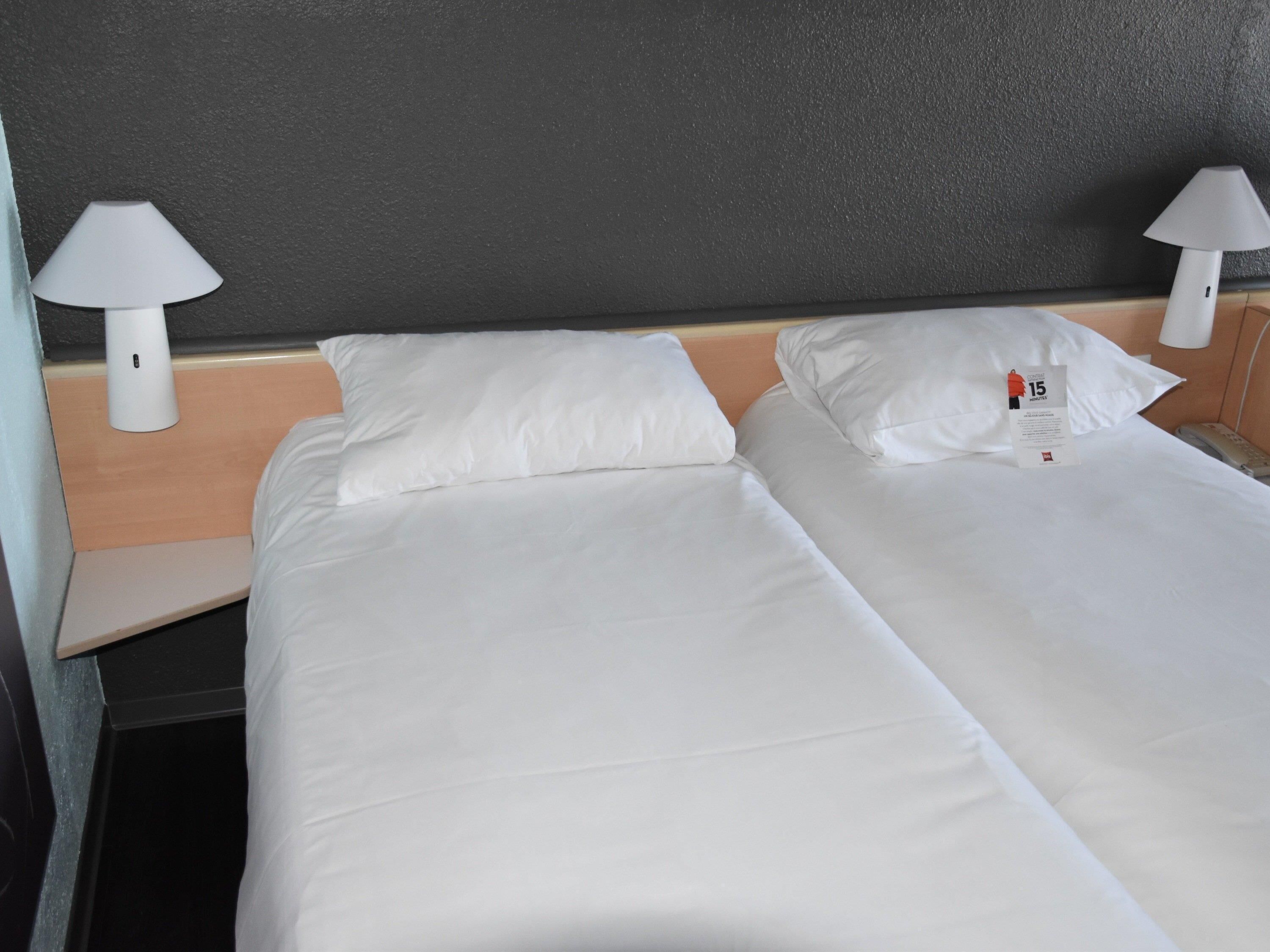 A hotel room with two beds, white linens, and two bedside lamps.