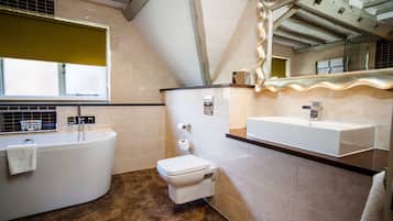 A modern bathroom with a freestanding bathtub, a toilet, and a vanity with a mirror.