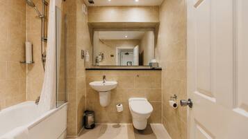 Un baño moderno con ducha, lavabo, inodoro y espejo.