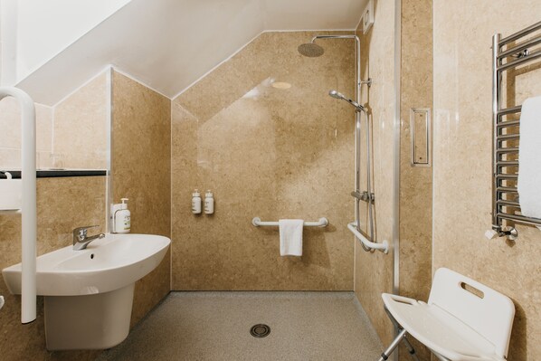 A bathroom with a sink, shower, and towel rack. - Rose and Crown Hotel (Salisbury)