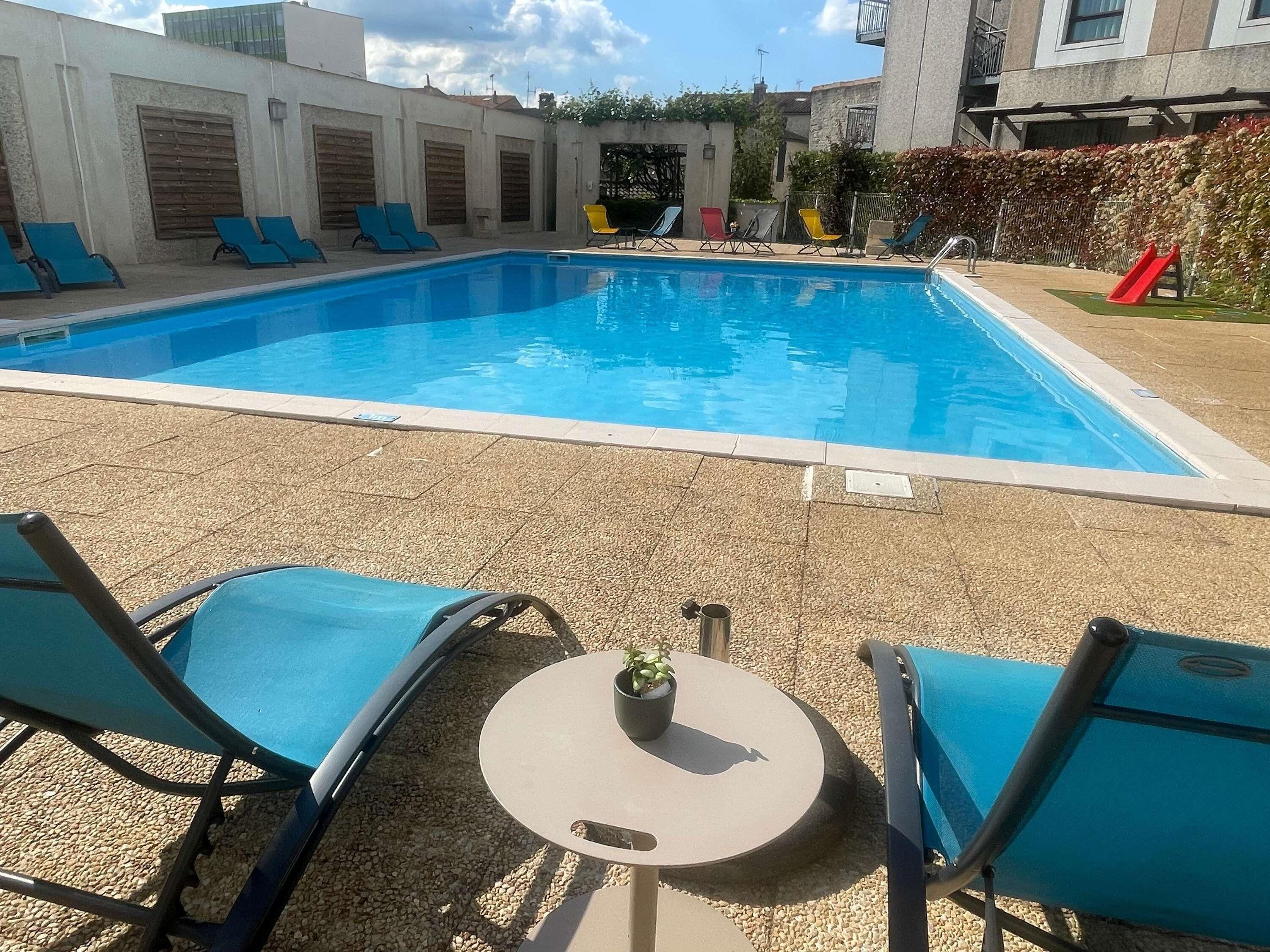 En swimmingpool med liggestole og et lille bord med en potteplante.