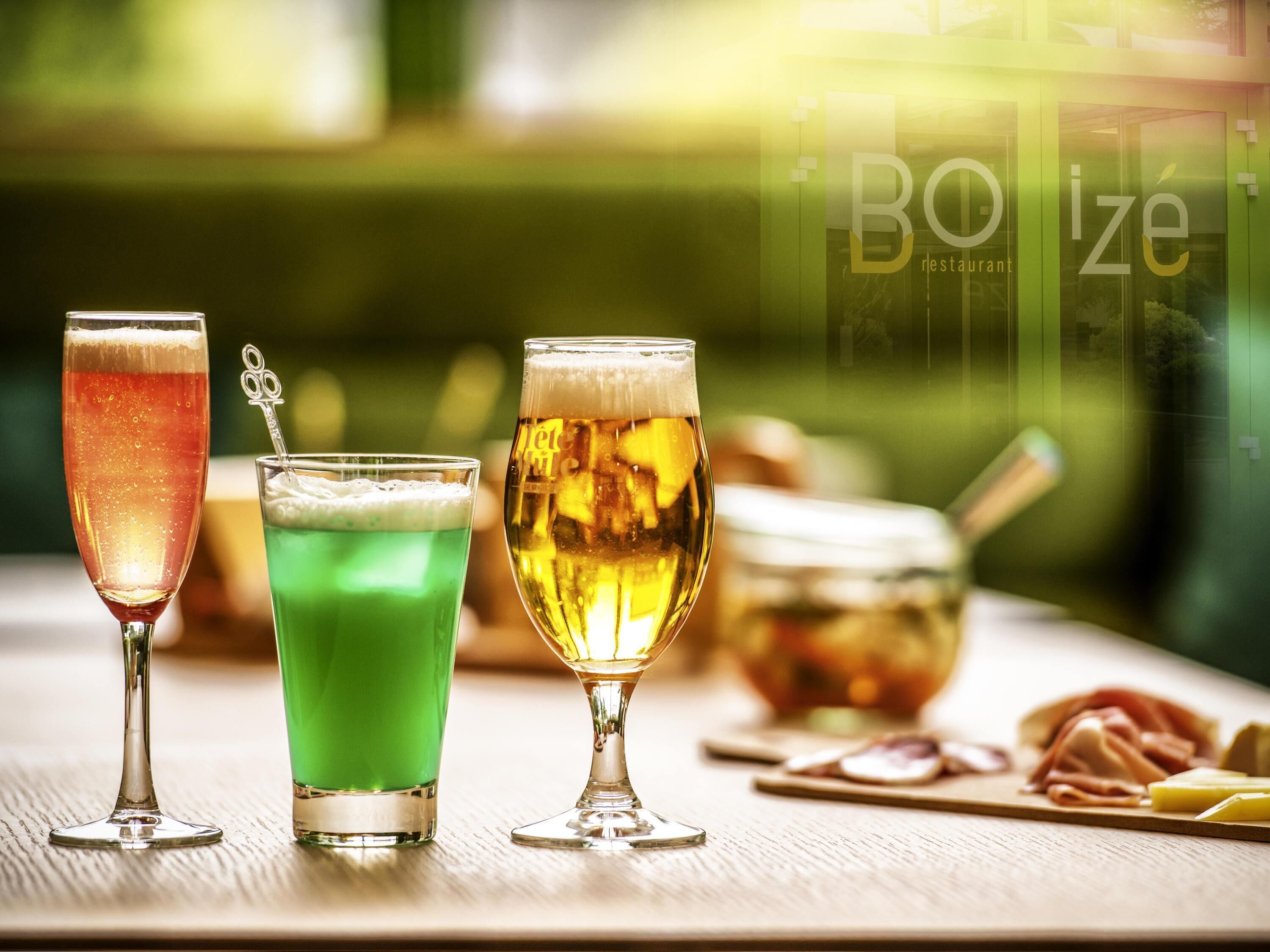 Three glasses of beverages on a wooden table with a blurred background.