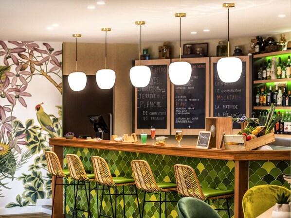 A bar area with wicker chairs, a wooden counter, and a menu board.
