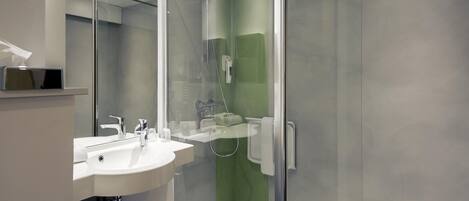 A modern bathroom with a glass-enclosed shower, a white sink, and a mirror.