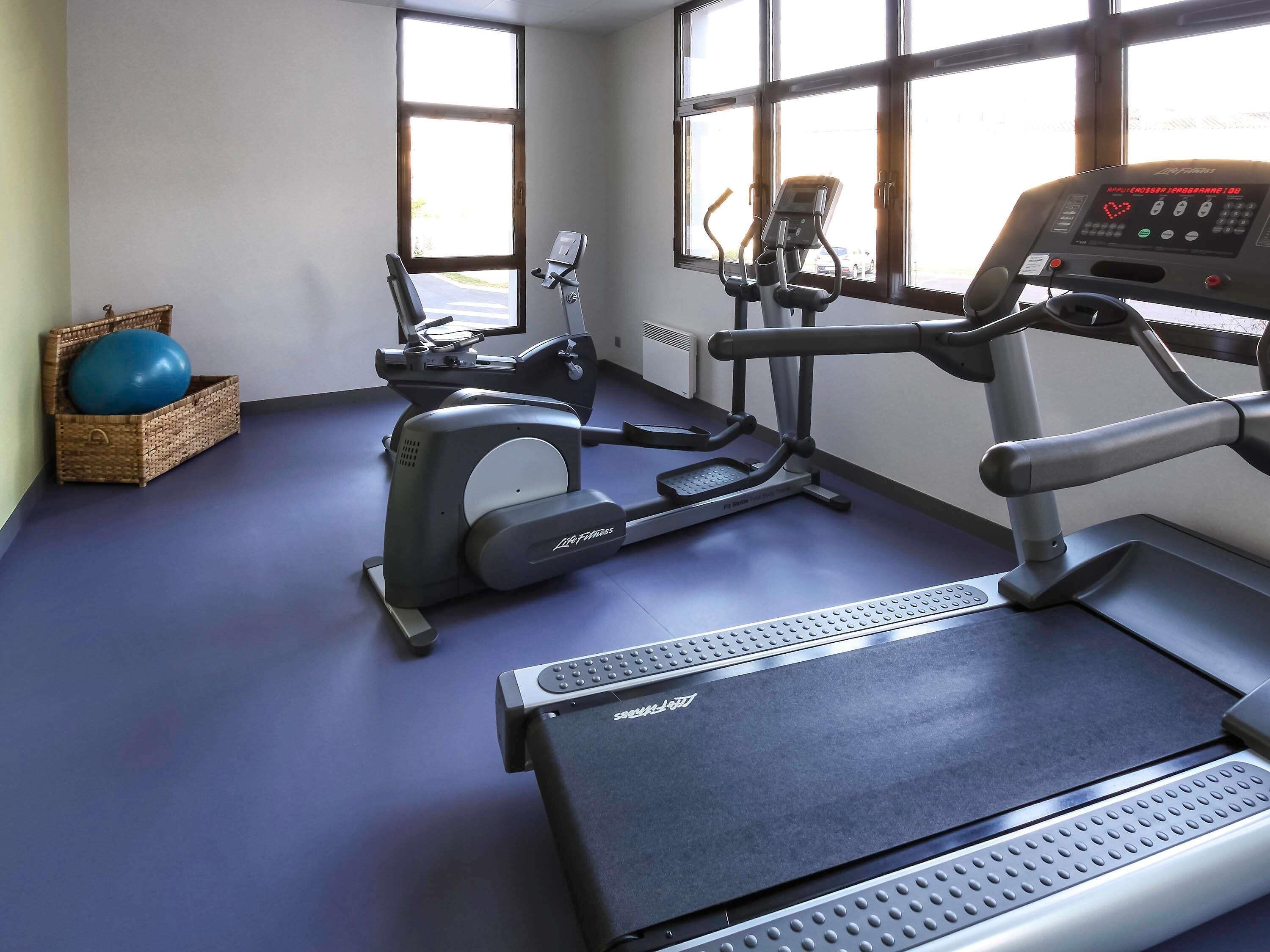 A gym with exercise equipment, a treadmill, and a stationary bike.