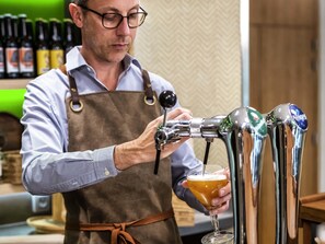 A bartender pouring a drink from a tap into a glass. - Mercure Niort Marais Poitevin (Niort)