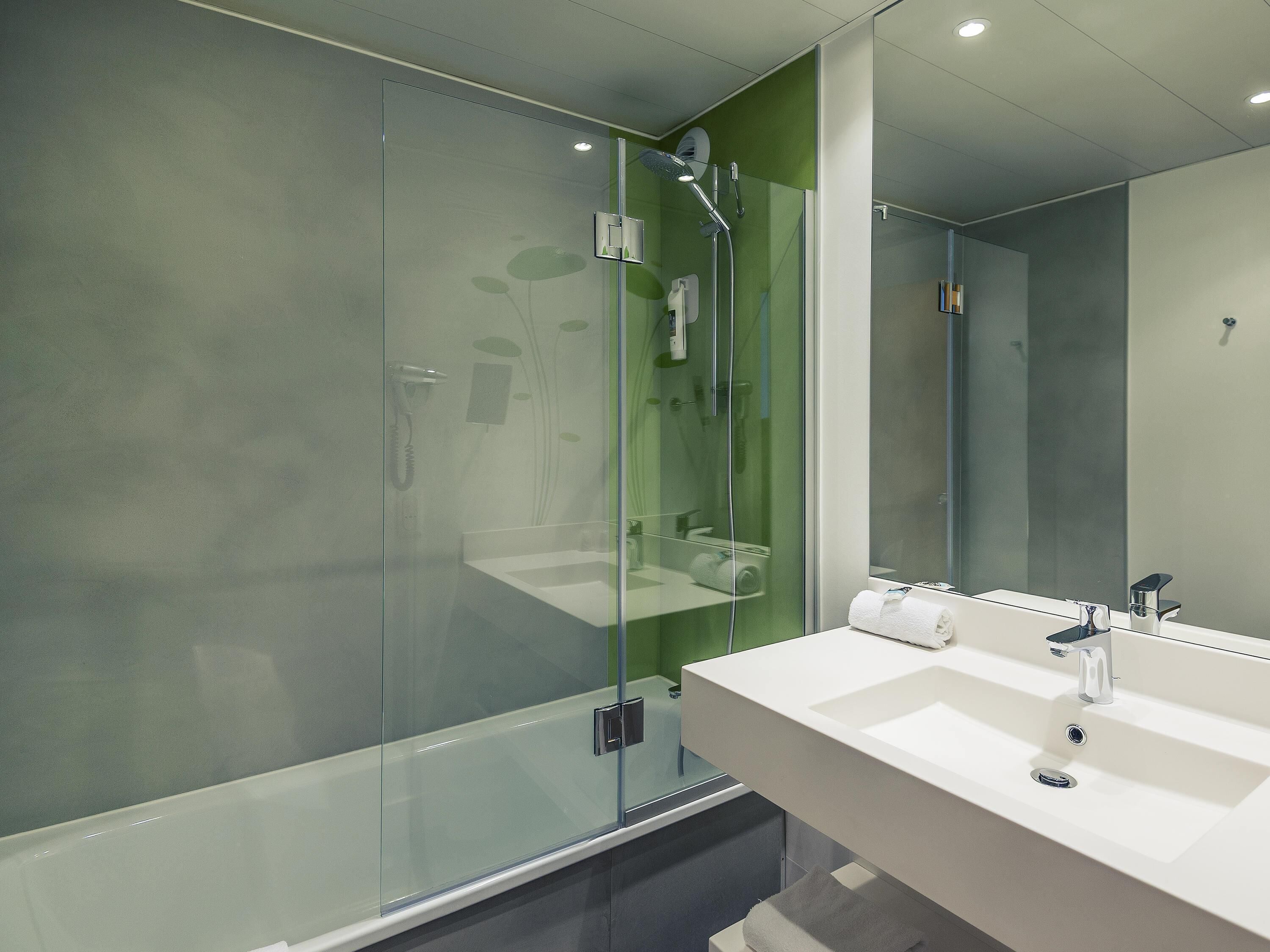 A modern bathroom with a glass shower enclosure, a white sink, and a large mirror.
