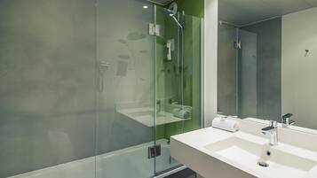 A modern bathroom with a glass shower enclosure, a white sink, and a large mirror.