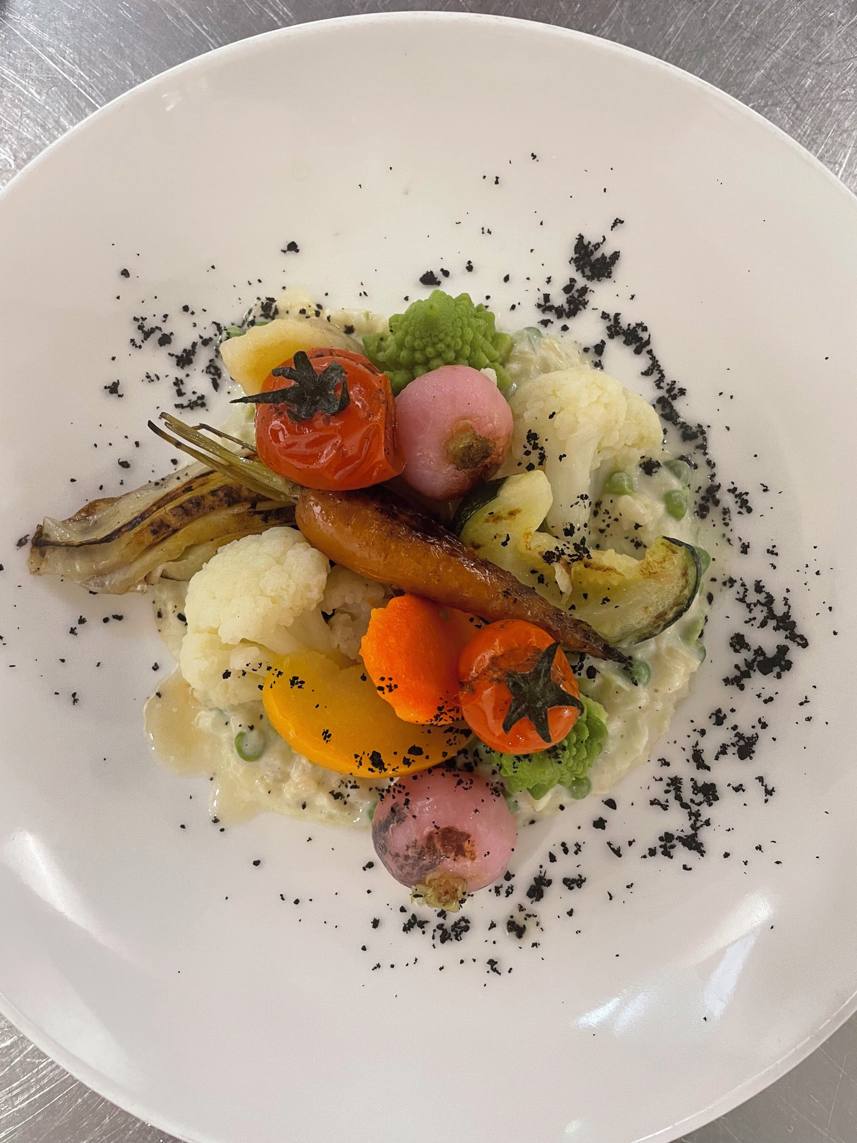 A white plate with a variety of vegetables and a sauce.