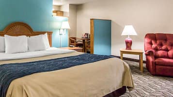 Une chambre d’hôtel avec un grand lit, un bureau, une chaise et une lampe.