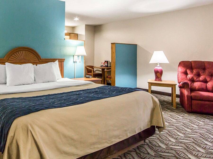 Une chambre d’hôtel avec un grand lit, un bureau, une chaise et une lampe.