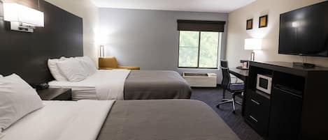 A hotel room with two beds, a desk, a television, and a window.