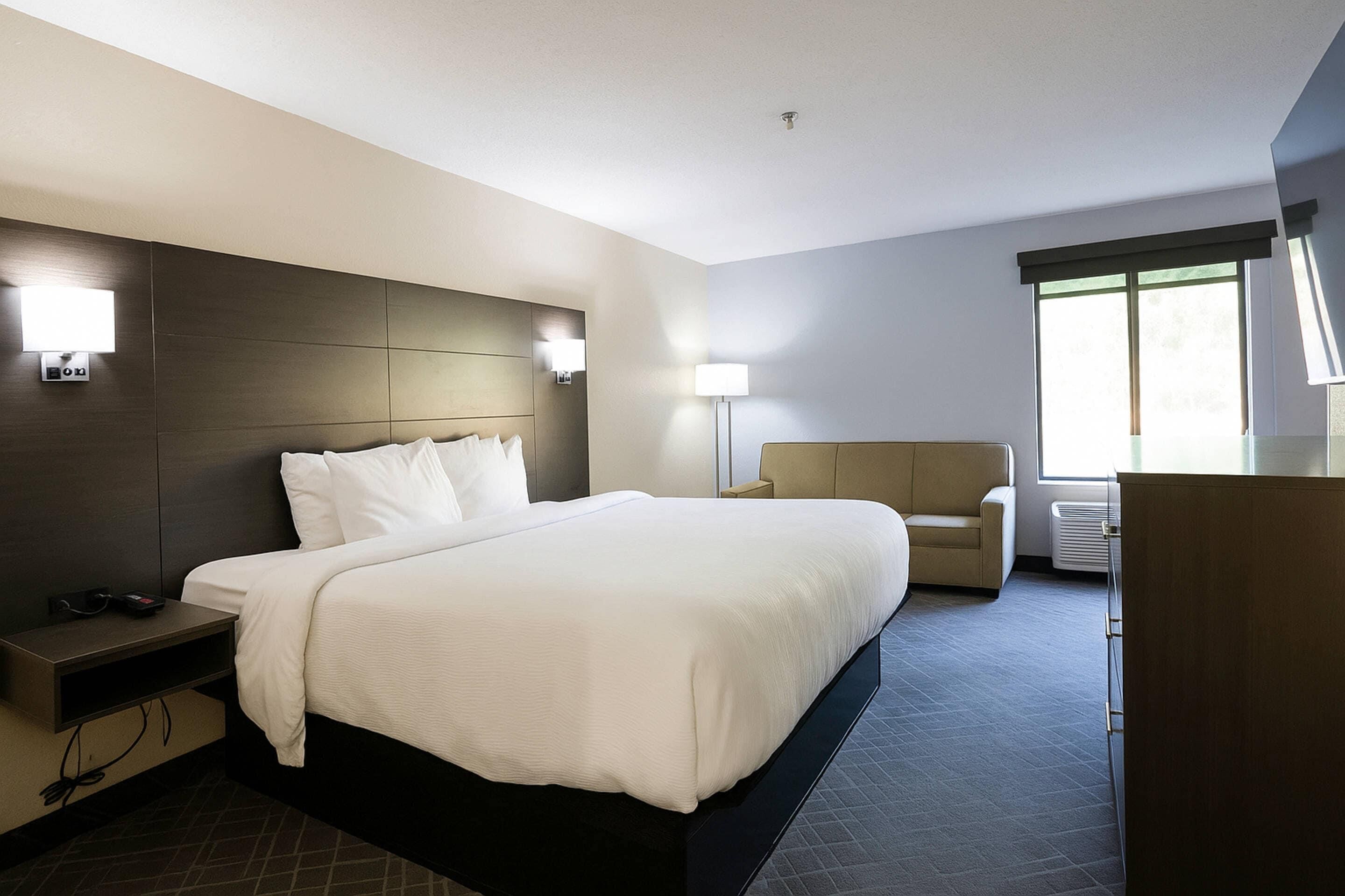 Ein modernes Hotelzimmer mit einem großen Bett, Nachttischen, einem Schreibtisch und einem Sessel.