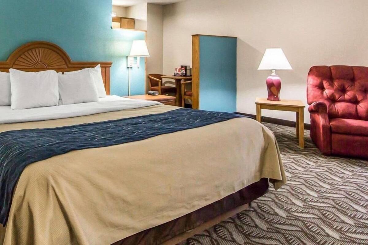Quarto de hotel com cama, escrivaninha, cadeira e abajur.