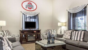 Una habitación de hotel con televisor, sofá y sillón.