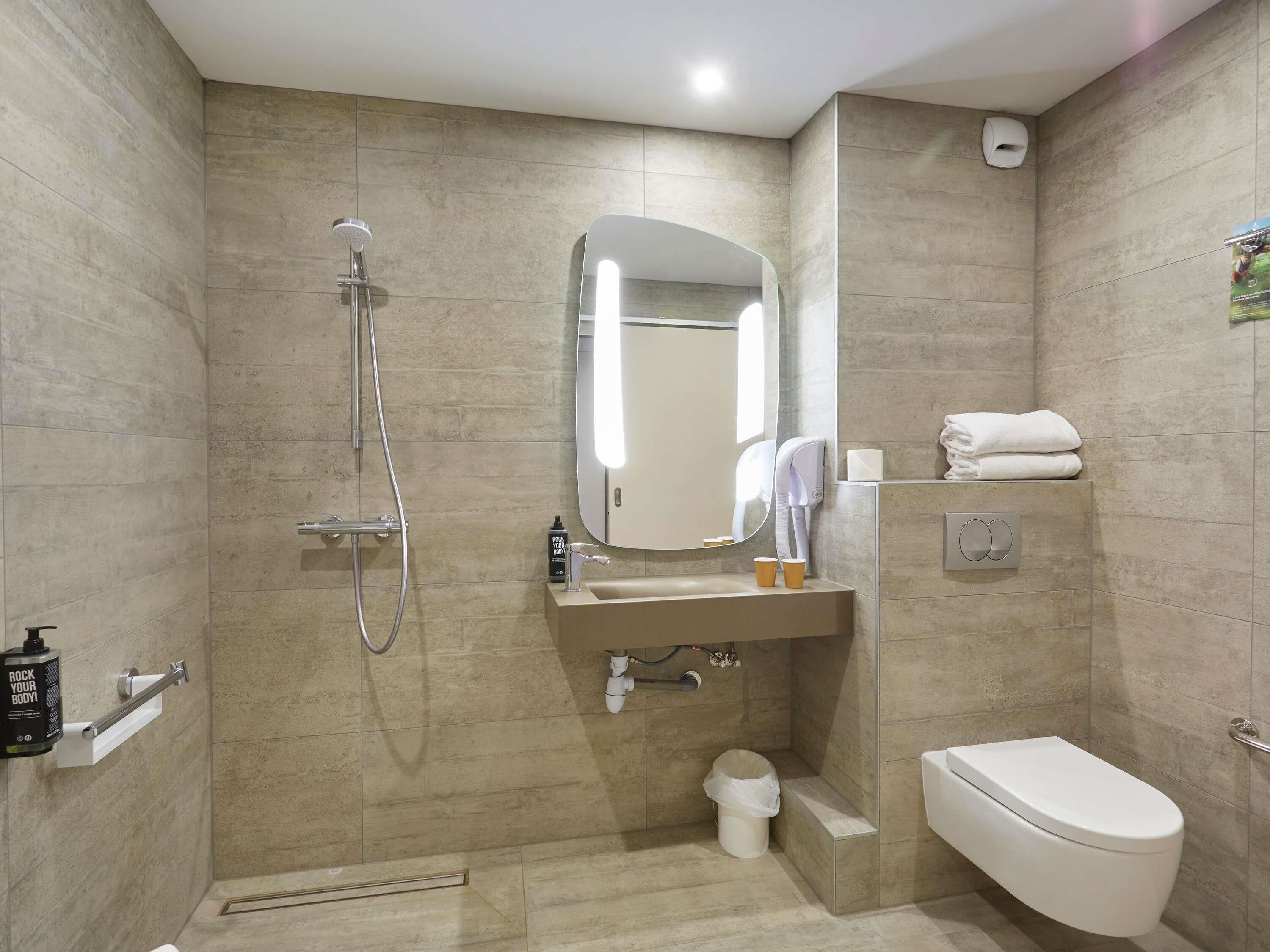 Une salle de bain équipée d’une douche, de toilettes, d’un lavabo et d’un miroir.