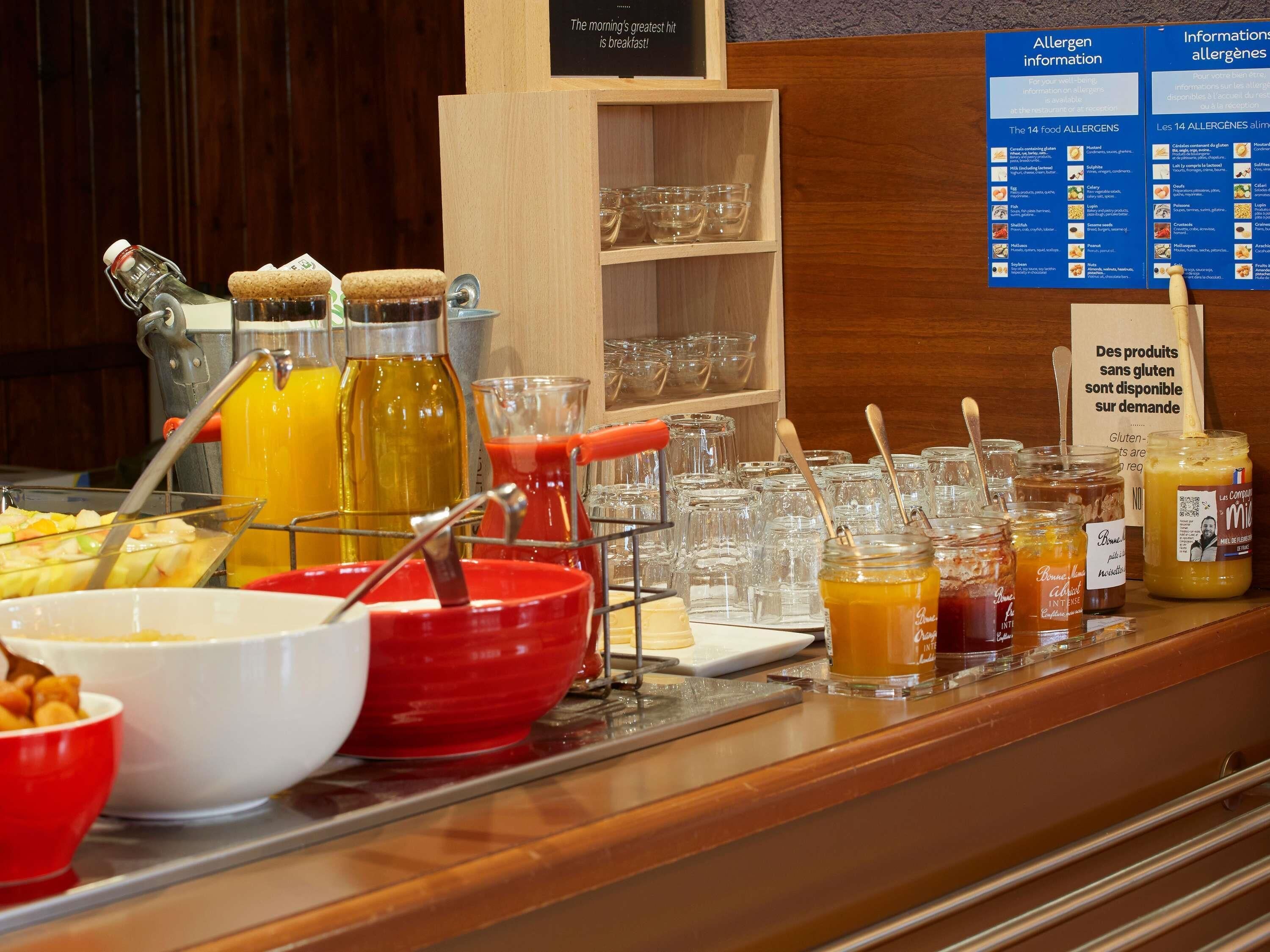 A buffet area with various food items and condiments, including jars of sauces and a selection of fruits.