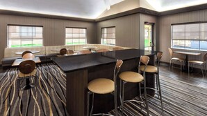 A modern hotel lobby with a central bar area, seating arrangements, and large windows offering views.