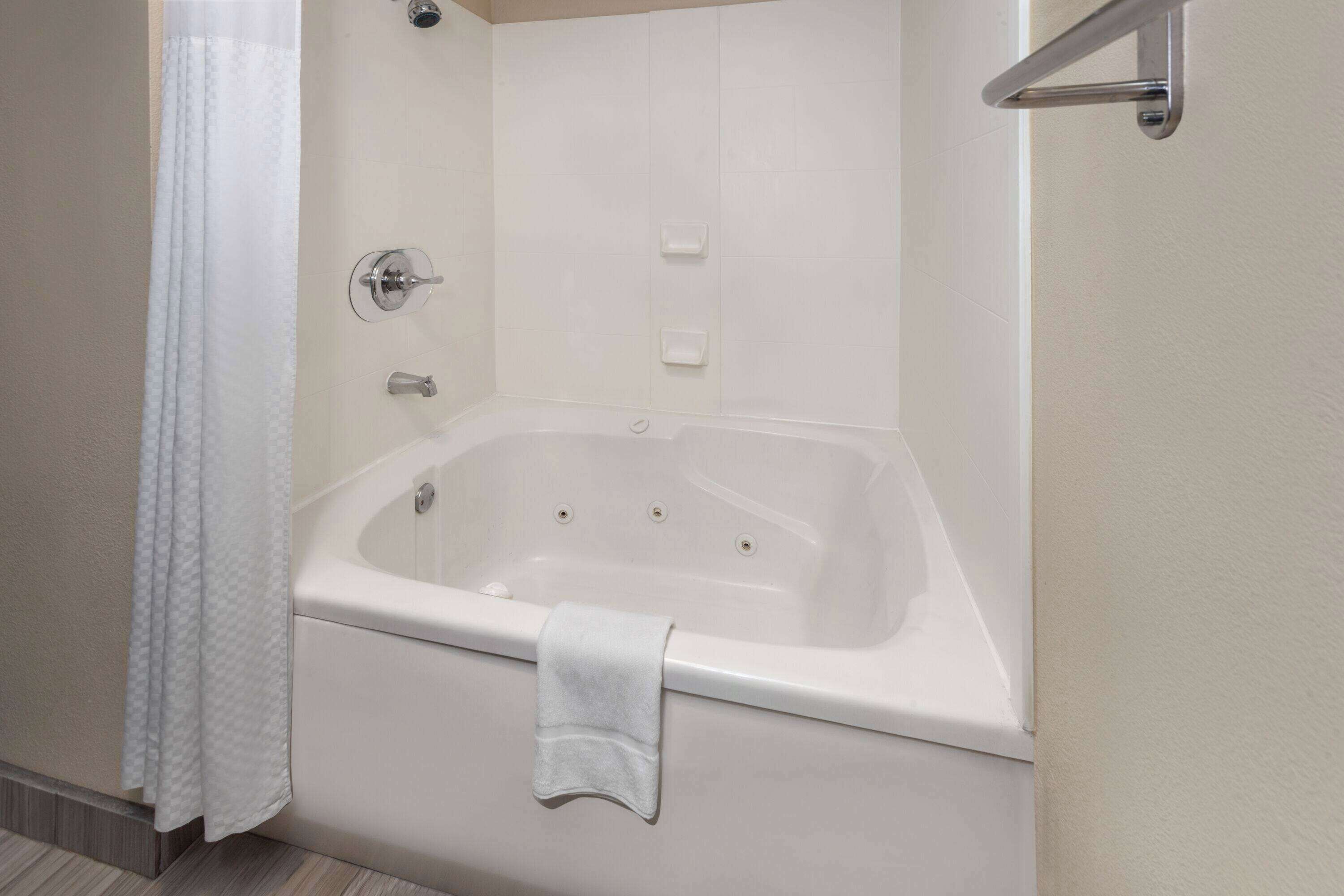 A modern bathroom with a freestanding bathtub, a shower curtain, and a towel rack.