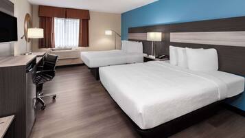A hotel room with two beds, a desk, a chair, a TV, and a window with curtains.