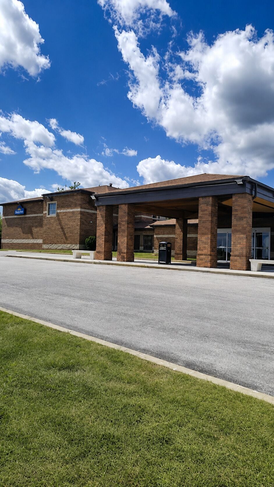 A building with a covered entrance, brick construction, and a clear sky with clouds.