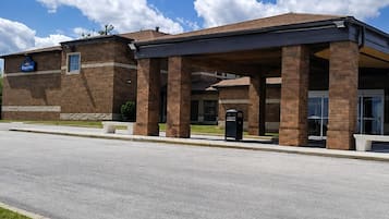 A building with a covered entrance, brick construction, and a clear sky with clouds.
