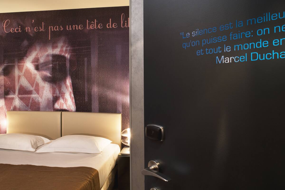 Habitación de hotel con una cama, un televisor de pared y una puerta con una cita.