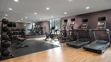 Un gimnasio con cintas de correr, elípticas y pesas sueltas.