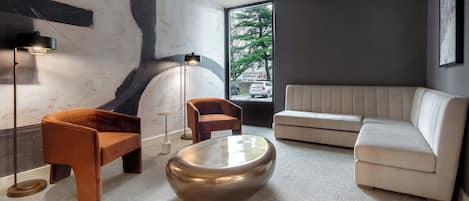 A modern living room with a sofa, two armchairs, a coffee table, and a large abstract painting on the wall.