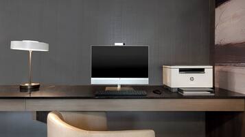 A modern office desk with a desktop computer, a printer, and a lamp.