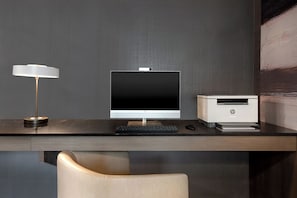 A modern office desk with a desktop computer, a printer, and a lamp.