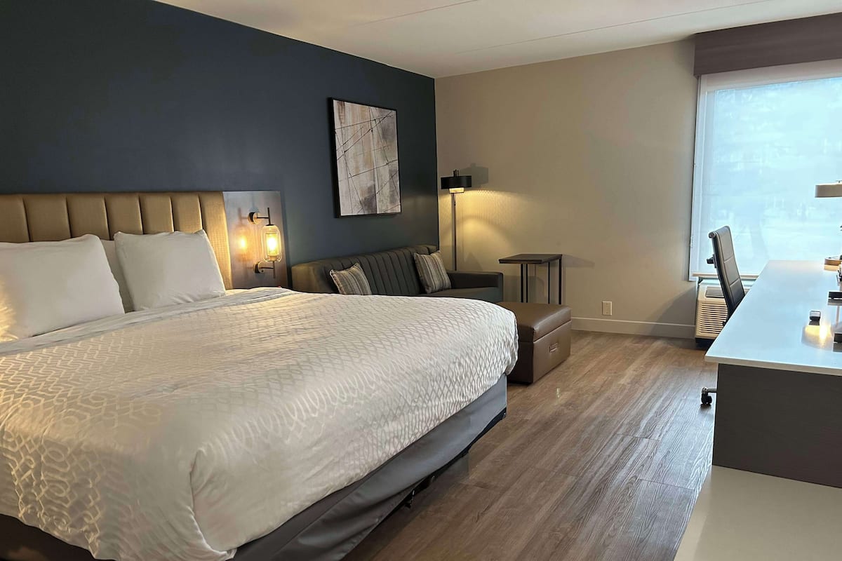 A hotel room with a large bed, a desk, and a chair.