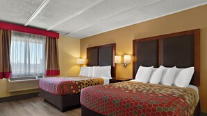 A hotel room with two beds, a window with curtains, wall-mounted lamps, and an air conditioning unit. - Kings House Motor Hotel, a Dazzler Select by Wyndham (Flagstaff)
