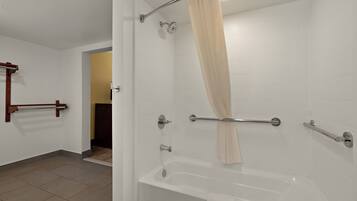 Un baño moderno con bañera, cortina de ducha y barras de apoyo.