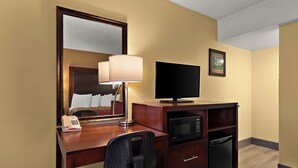A hotel room with a desk, chair, television, microwave, and refrigerator. - Kings House Motor Hotel, a Dazzler Select by Wyndham (Flagstaff)