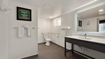 Un baño moderno con un lavamanos, espejo y retrete blancos. Un letrero en la pared dice: "Welcome to Flagstaff Arizona".
