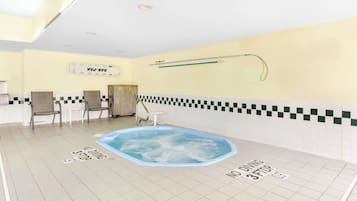 Un espace piscine comprenant un jacuzzi, des sièges et un panneau indiquant qu’il est interdit de plonger.
