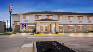 A Comfort Inn hotel with a covered entrance, a parking lot, and a landscaped area with flowers.