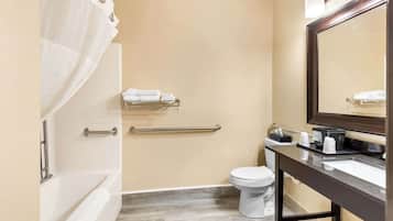 Un baño moderno con bañera, inodoro y tocador con espejo.