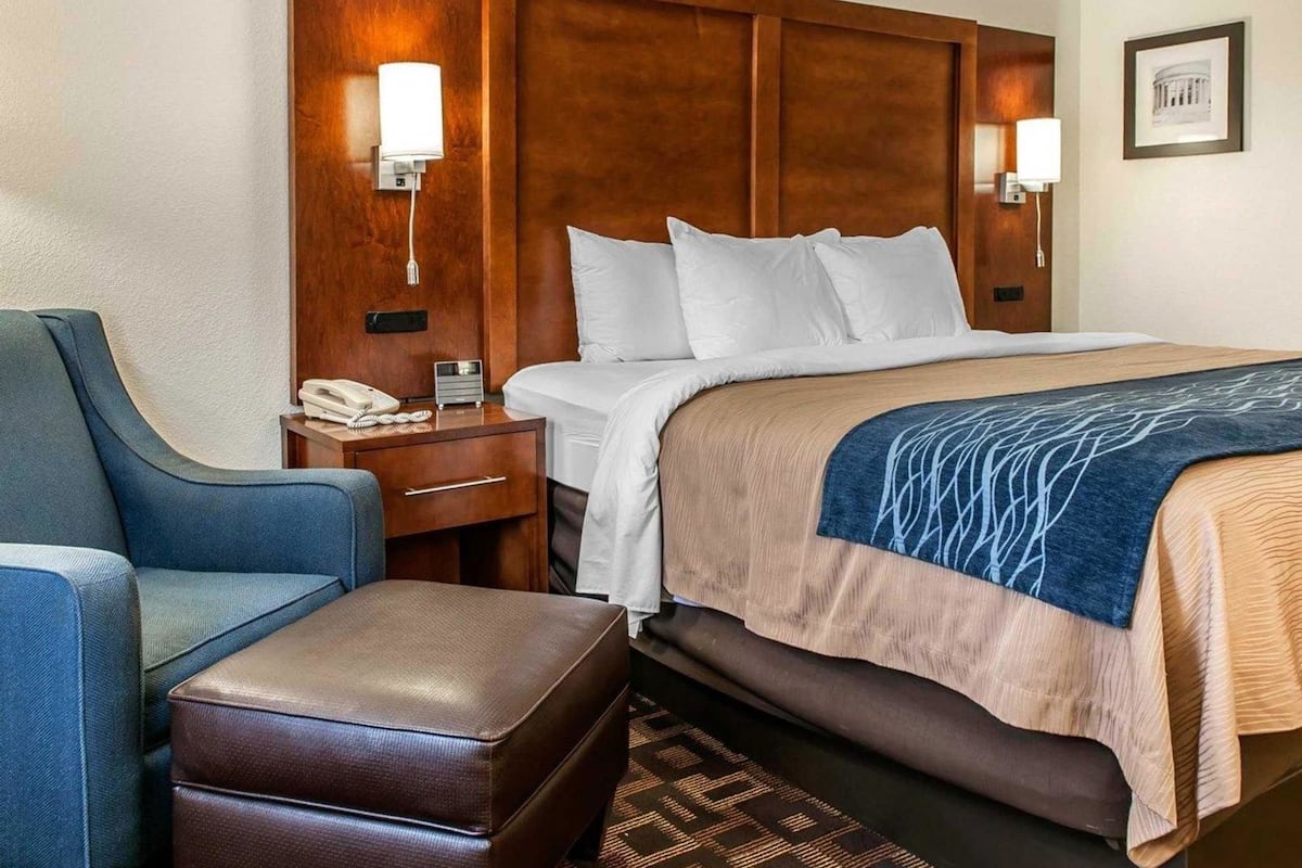 A hotel room with a bed, a desk, a chair, and a telephone.