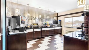 A modern kitchen with a herringbone tile floor, stainless steel appliances, and pendant lighting.