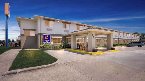 A Comfort Inn hotel with a covered entrance, a parking lot, and a well-maintained lawn.
