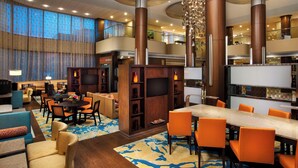 Un hall d’hôtel comprenant un espace repas, des sièges et un téléviseur.